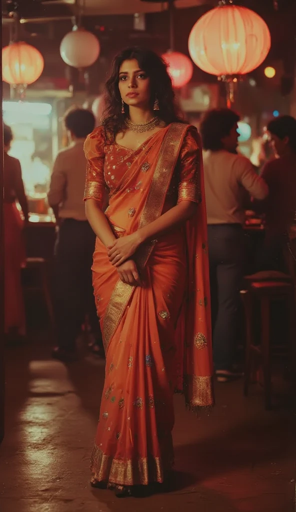 A tall, hourglass-shaped woman with a slightly fuller figure stands gracefully at a lively party, her posture confident and dignified. She faces the camera, hands straight down together in front of her, embodying poise and elegance. She wears an exquisite Indian-style outfit made from soft, orange pure velvet fabric, richly adorned with multicolored mirror stonework across the saree. The high-neck design adds a modern touch, while exaggerated, puffy shoulders introduce a dramatic flair, making her silhouette captivating. The outfit’s 3/4 sleeves add an extra layer of refinement, complementing the overall regal aesthetic. High heels elevate her stature, further emphasizing her poised stance and exuding an aura of sophistication and allure, captivating everyone in the room.