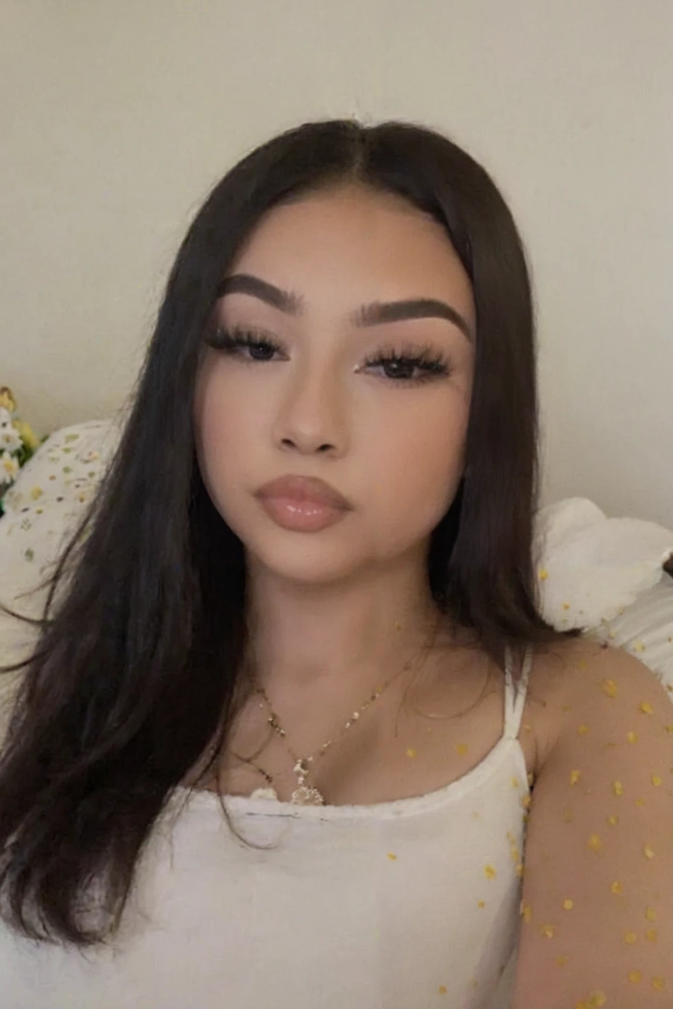 Close-up photography of the face of a beautiful 18 years old, wearing copypaste makeup, taking selfie, laying in bed, wearing white, slightly darker lighting