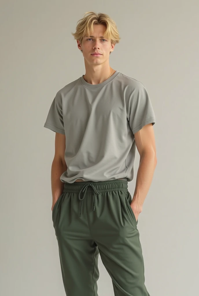  white boy with blond hair wearing slightly baggy, dark green tracksuit trousers and a light grey t-shirt