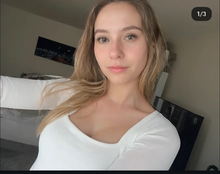A 23-year-old blonde woman., ((pechos grandes)), ((hiperrealismo)) ,. blonde hair with light brown roots. cabello rubio, Hair with brown roots, cabello extra largo, cabello muy largo, pelo muy largo, hermoso, vista frontal, autofoto, foto tomada con iPhone, elegante camisa negra con escote, escotada, autofoto in the bed, Alta calidad, autofoto iPhone, escote, Varias poses comienso