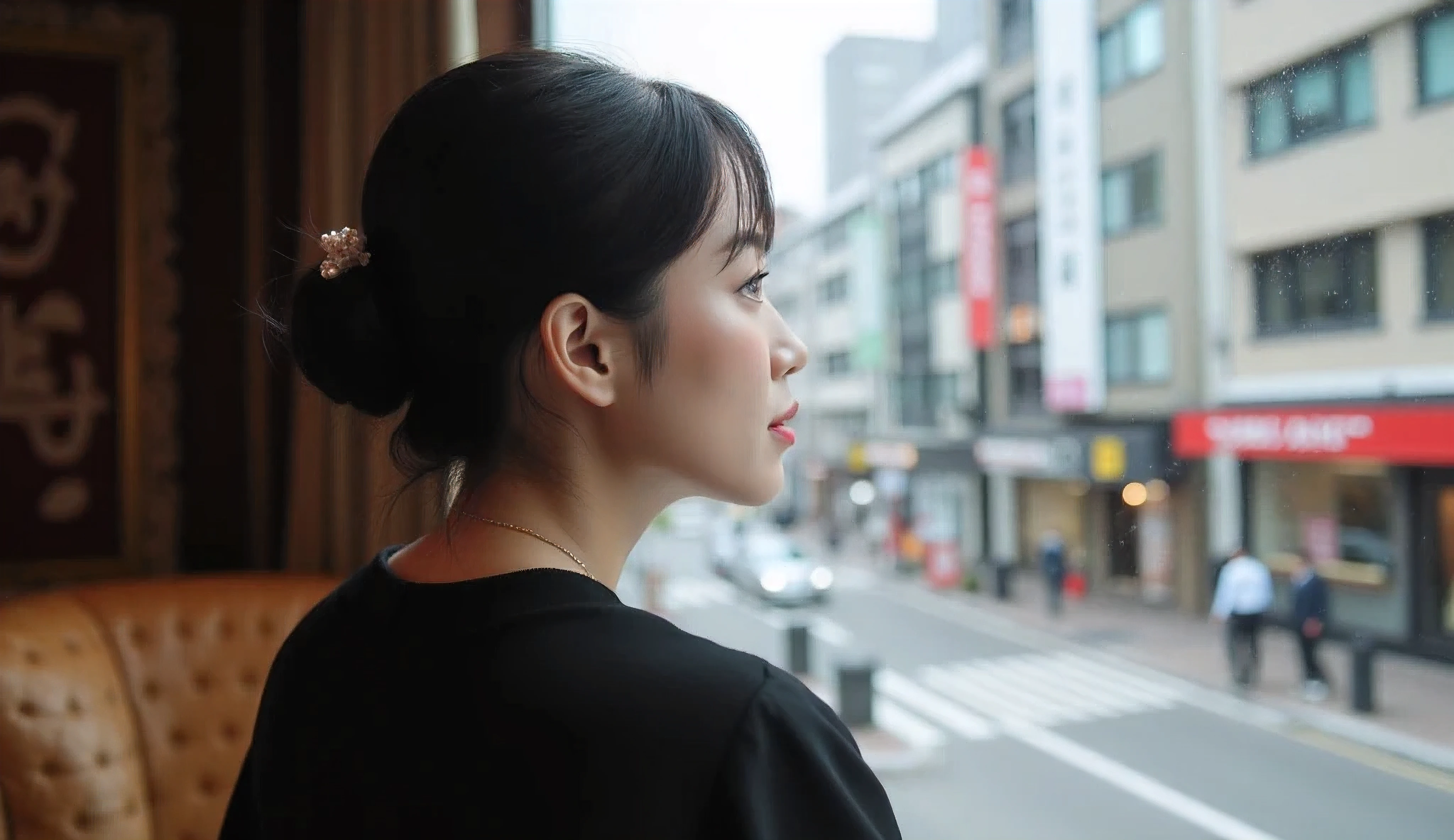 A Japanese woman in her 40s in chic clothes sitting by the window and looking at the streetscape