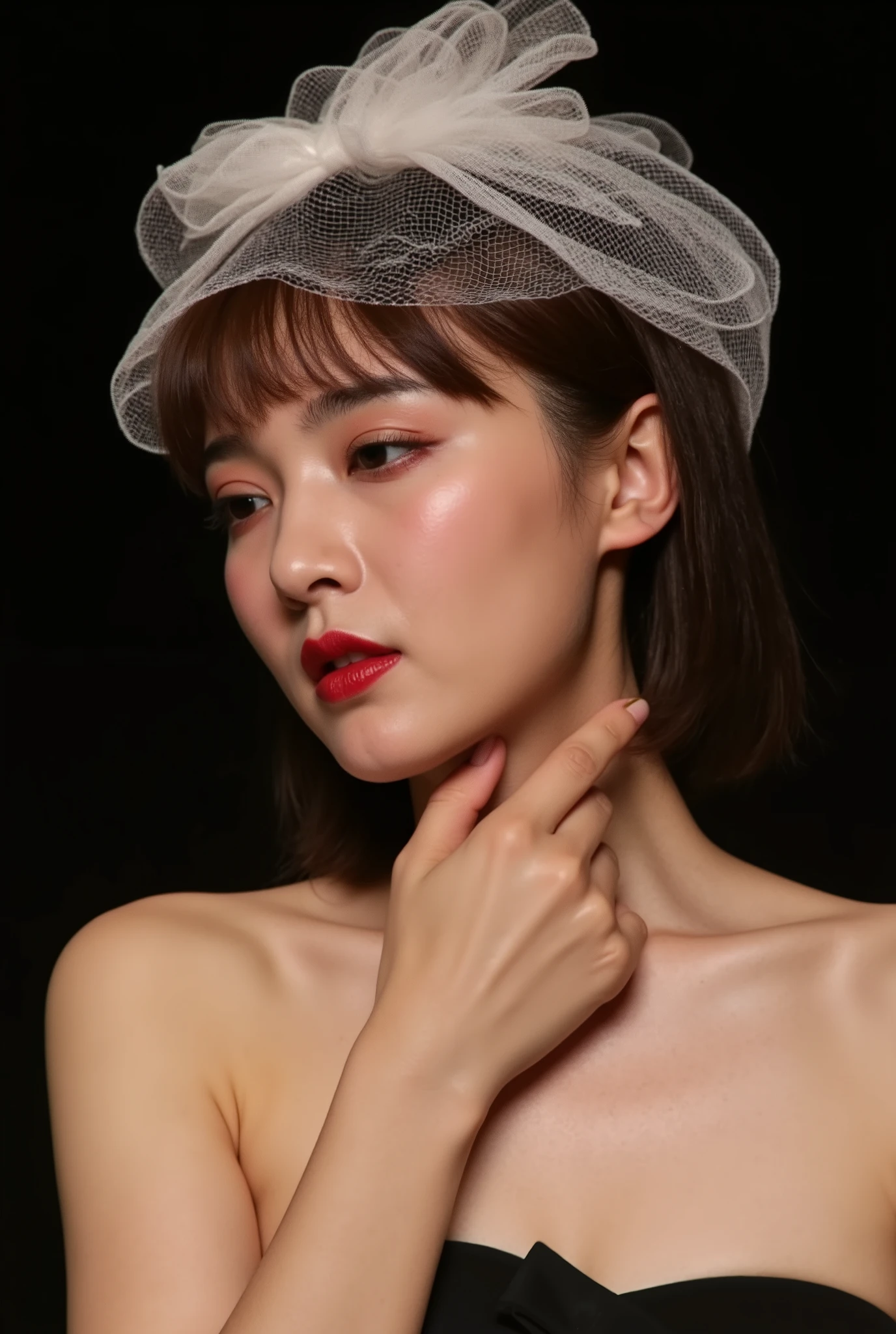 Young woman, fair complexion, straight medium-length brown hair with bangs, delicate petite frame, slight hourglass figure.Outfit: black strapless top, revealing shoulders and part of chest, modest breast size. Makeup: minimal yet elegant, focusing on natural features; well-defined eyebrows, full deep red lips, subtle eye makeup highlighting almond-shaped eyes.Head adorned with delicate white sheer veil, bow detail, adding femininity and whimsy. Right hand gently touching neck, fingers slightly curled, thumb resting on collarbone, soft delicate pose.Background: solid deep black, contrasting with pale skin and light clothing, making her the focal point. Soft even lighting casting gentle glow, highlighting facial features and texture of hair and clothing. Overall mood: serene and intimate, capturing moment of quiet contemplation.