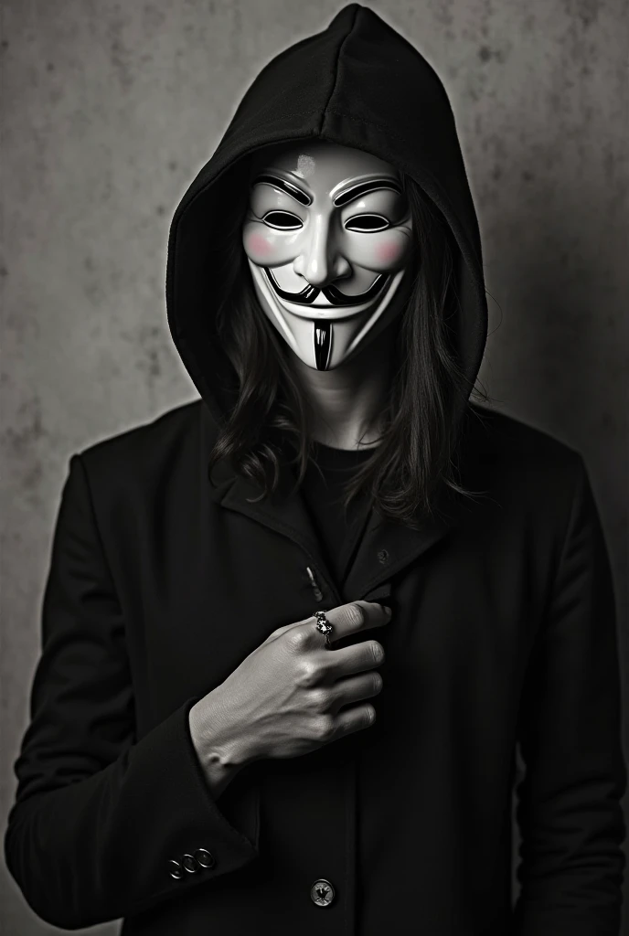 A person with medium-length, messy dark hair is wearing a white hoodie and a stylized Guy Fawkes mask. The mask covers their entire face, and they are also wearing round eyeglasses over the mask. The individual is holding their hand up to their chest, with several rings visible on their fingers. The lighting in the image is dim, with a dark and moody ambiance, giving the entire scene a somewhat mysterious and rebellious atmosphere. The background is blurry and out of focus, emphasizing the person as the main subject of the image.