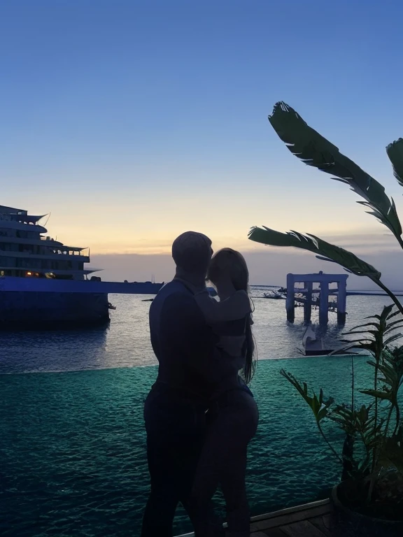 Long blonde straight haired female, curvy, red lips and a rugged man who has dark hair and beard kissing beneath a gazebo