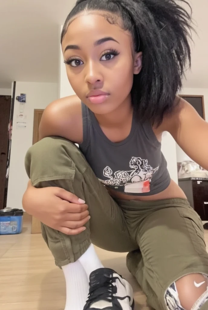 On her knees a picture of a slim thick pretty black girl from Atlanta black baddie girl with a video aesthetic with a nice define chiseled jawline with almond slanted shape eyes and she is taking a  selfie at home wearing a  graphic shirt and cargo pants  and Nike sneakers 