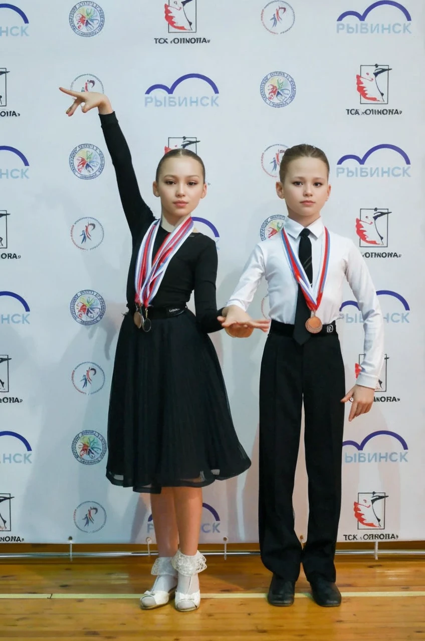 two young figure skaters,they are posing for a picture in front of a canadian flag,