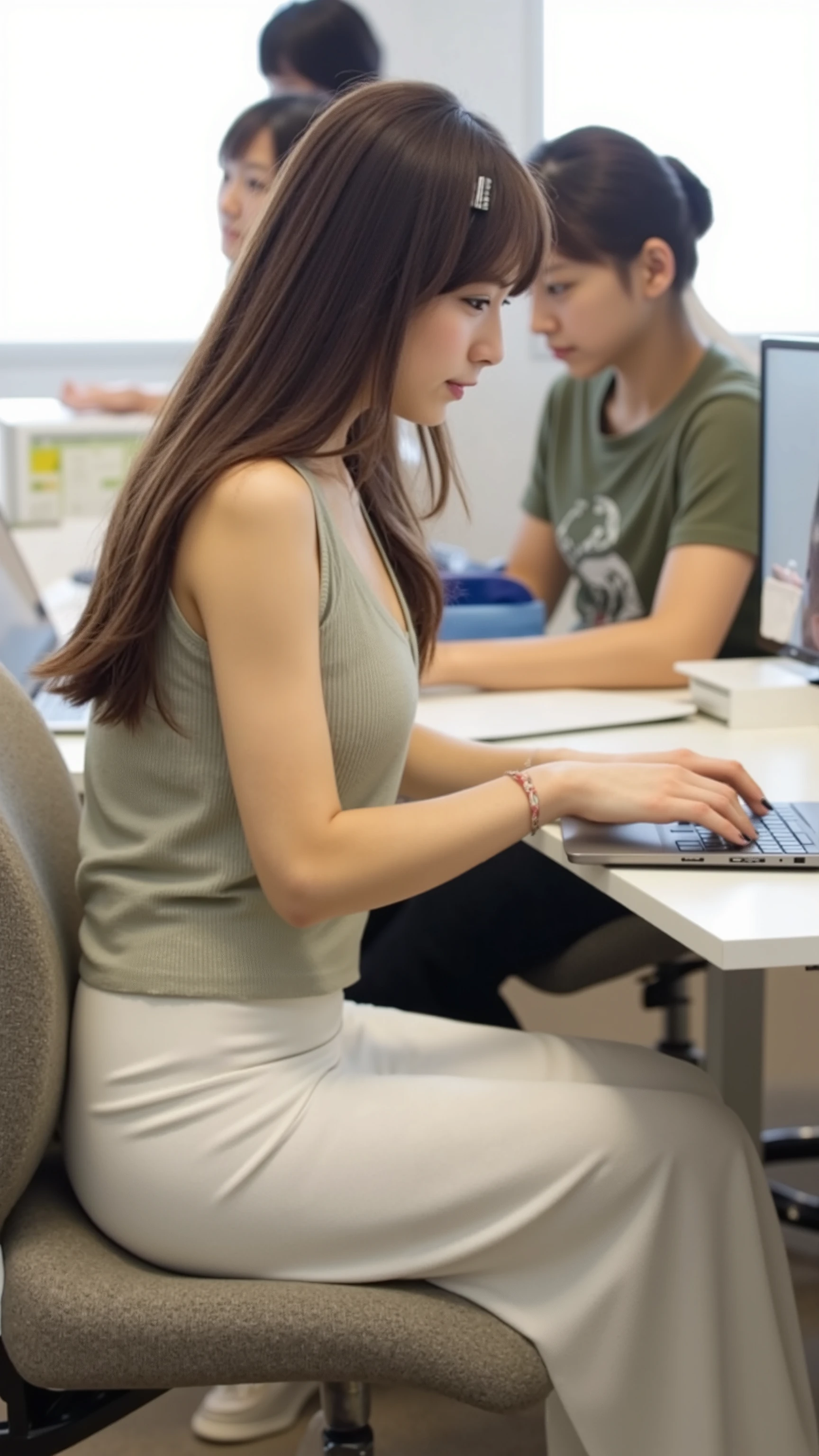 A photorealistic image of a young Japanese woman in her 20s sitting at her desk in a busy Tokyo office. She is viewed from the side, with her full body visible. She has long black hair tied with a hair clip and is wearing a soft, V-neck, lightweight knit top and a thin white, form-fitting long skirt. She is sitting upright on an office chair, working intently on a laptop. Her expression is calm and focused. The camera is positioned at her side, showing her entire figure and workspace clearly. She is not wearing glasses. The viewer is not shown in the image. The background shows other people working, creating a lively office atmosphere.
