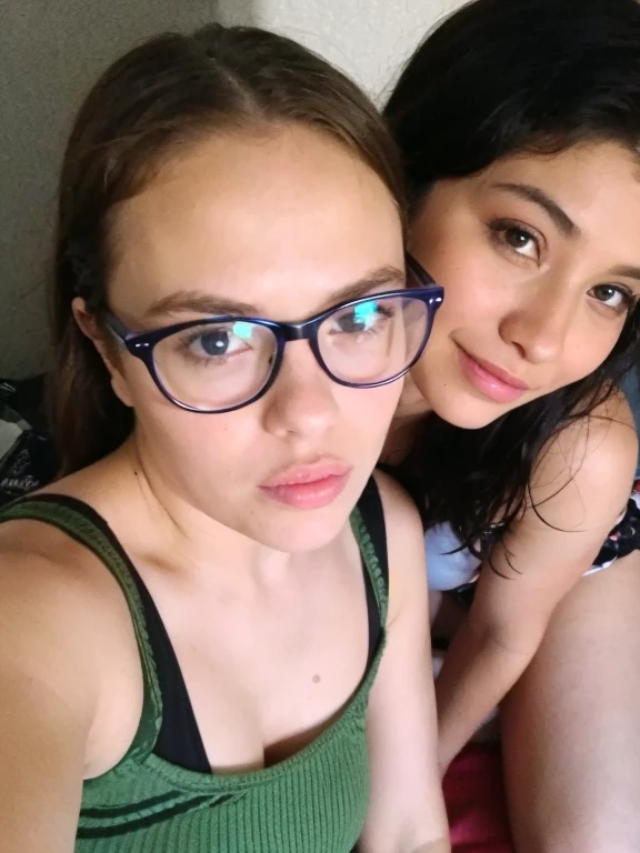 A photo of a two headed 110 pound girl with dark brown hair with a bright red streak in the hair on both heads. She is Italian with a large nose. She has small uneven breasts. Both of her two heads wear glasses. She is wearing black sweatpants and a black tank top. She wears a black choker with the name Kitty on it. She has tattoos on her arms. She is laying on bed alone smoking weed and playing with herself in her pants awkwardly and embarrassed as she shits her pants. 