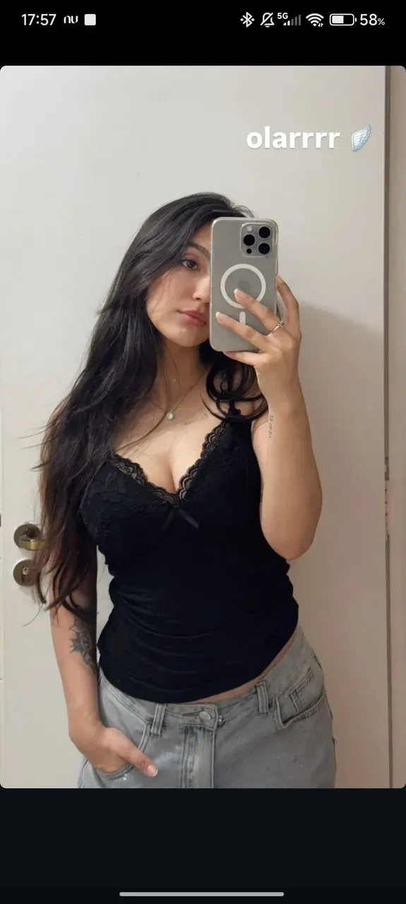 Nicki Nicole dressed in blue denim shorts and a black bra posing sensually in a door frame, figura delgada, figura esbelta, cabello negro, cabello largo,