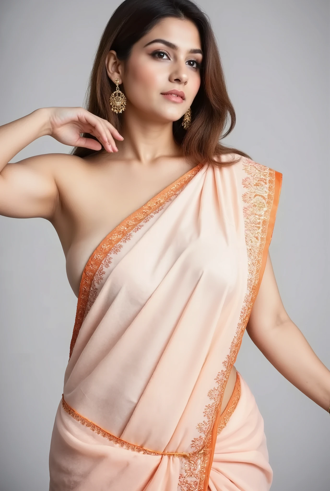 A woman is wearing a revealing light peach-colored saree with a subtle gold border and intricate patterns. The saree is draped traditionally over her left shoulder. She has medium-length, dark brown hair that falls loosely around her shoulders. She is wearing large, ornate earrings and a small pendant necklace. Her right arm is extended outwards, and her left hand rests on her waist. The background is a plain, light gray or off-white color. The lighting is even and bright, creating a soft and natural look. The overall style is elegant and graceful.