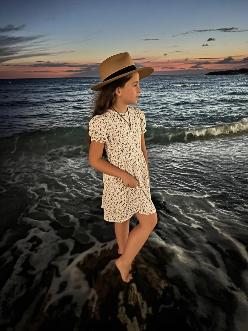 Image on the beach A child girl with long brown hair wears a long cold blouse and wearing a light green New York cap full body image