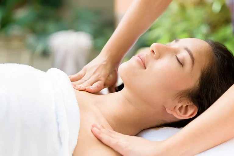 A woman lying face down receiving an oil massage
