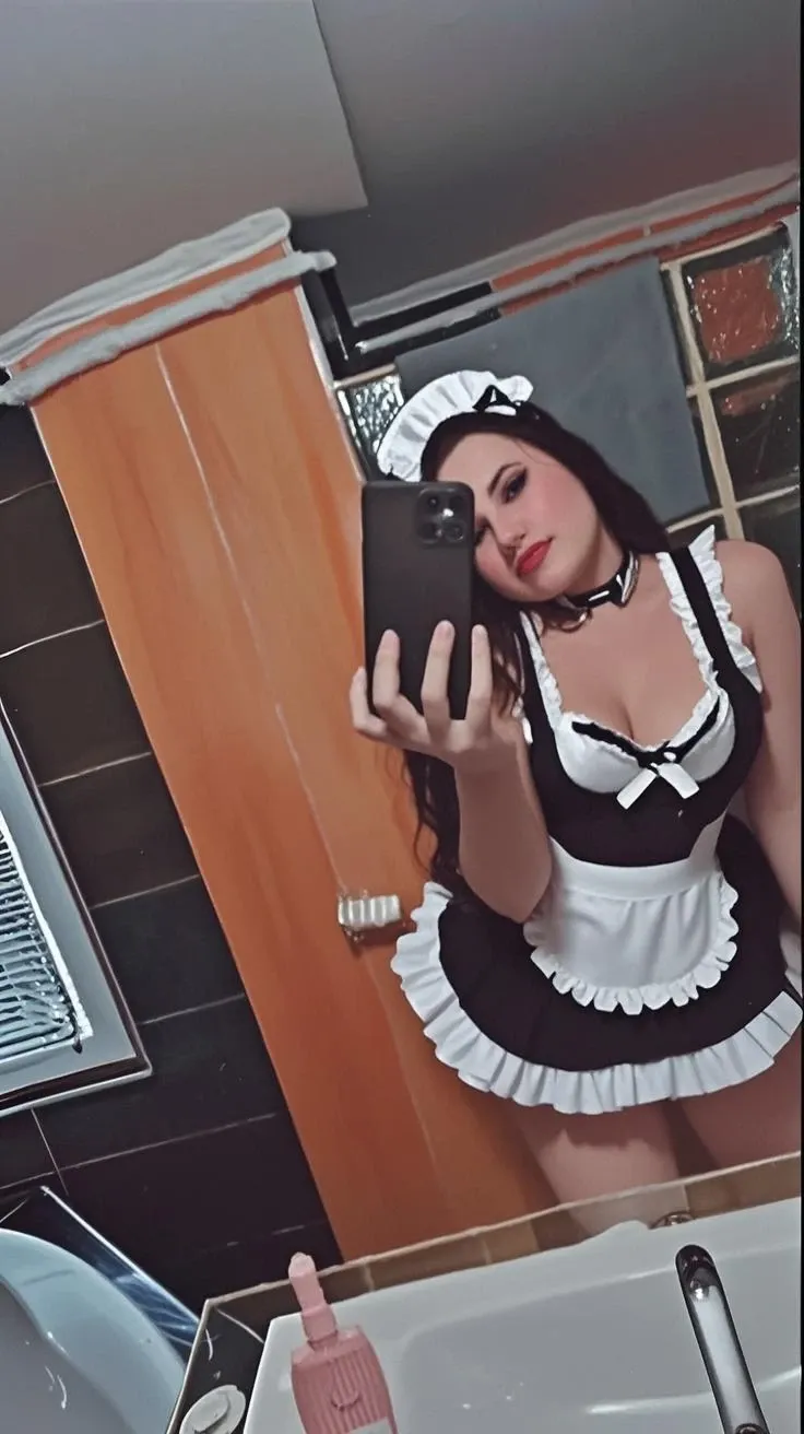 woman taking a selfie in the bathroom mirror dressed like an slut,