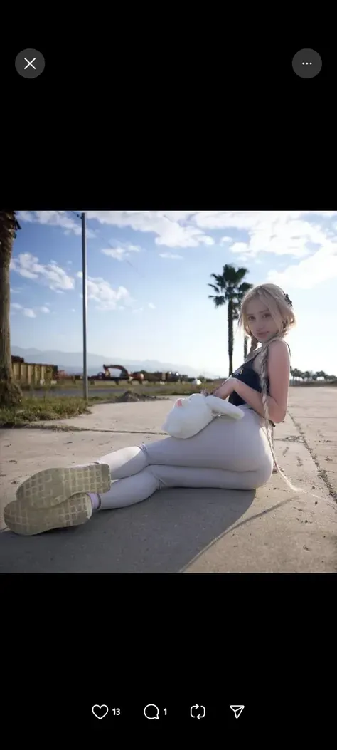 Short-haired girl with cat ears in very tight revealing bikini with white sneakers on the beach smiling at the camera touching her breasts