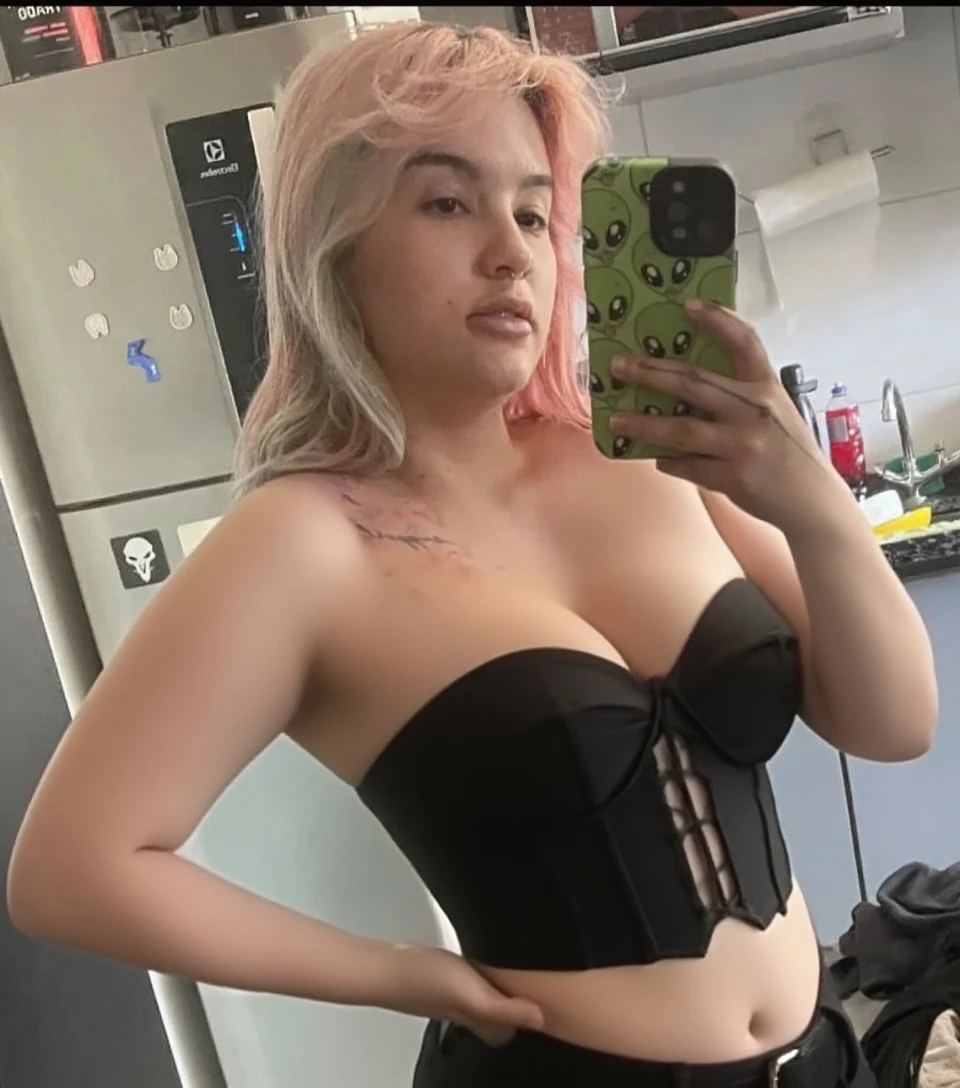 Cute fiveteen year old girl with chibi face. Hair is half yellow half blue. snow colored skin. eepy expression. taking a selfie while standing at a mirror. wearing Black tight laced bikini, massive breast. Long, messy blue and yellow hair. american.