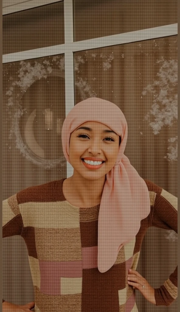 girl wearing glasses and hijab and lipstick smiling wearing leggings with both arms up in the air