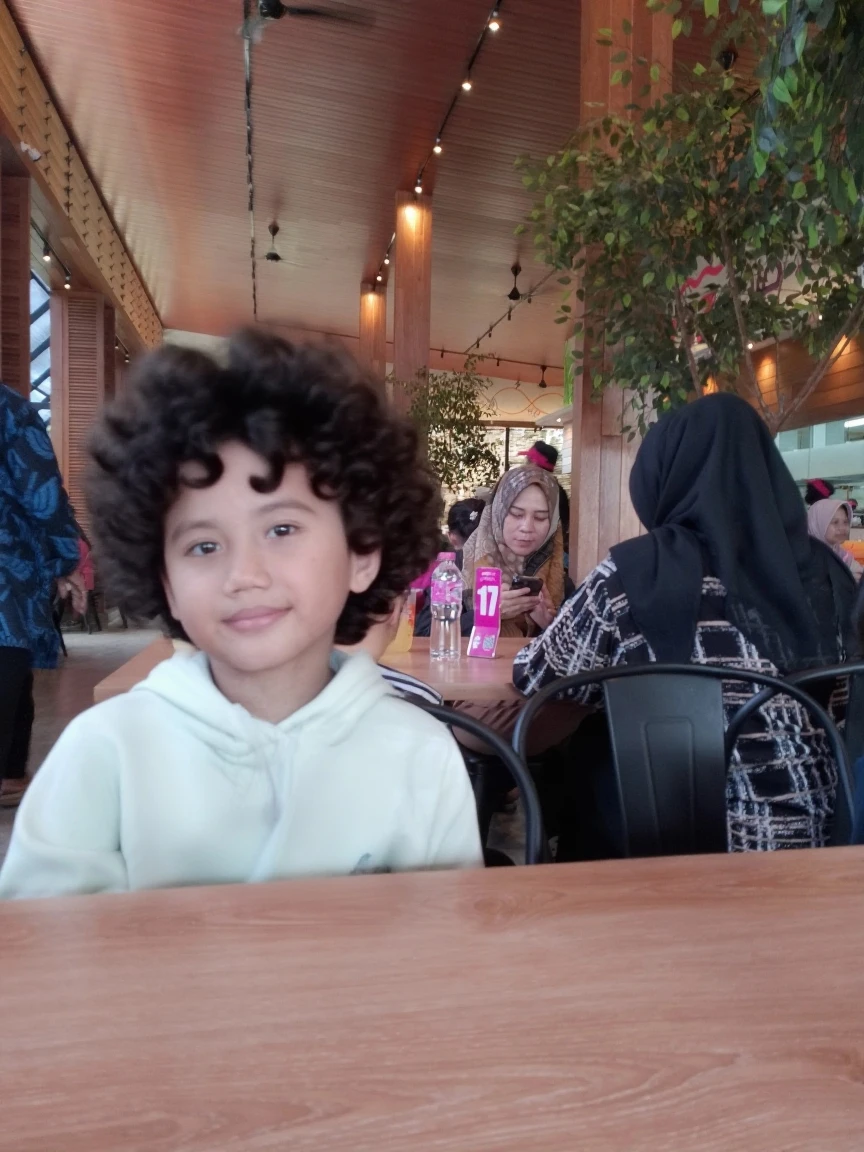 There's a boy sitting at a table with a cake, Santiago, menino com rosto neutro, Reyyan, imagem de qualidade muito baixa, Tomado com Sony Alpha 9, Riyahd Cassiem, cabrito, mateus 9 5, with a sad expression, Tiro na Nikon Z9, Mohamed Reda, em um shopping, Mohamed Chahin