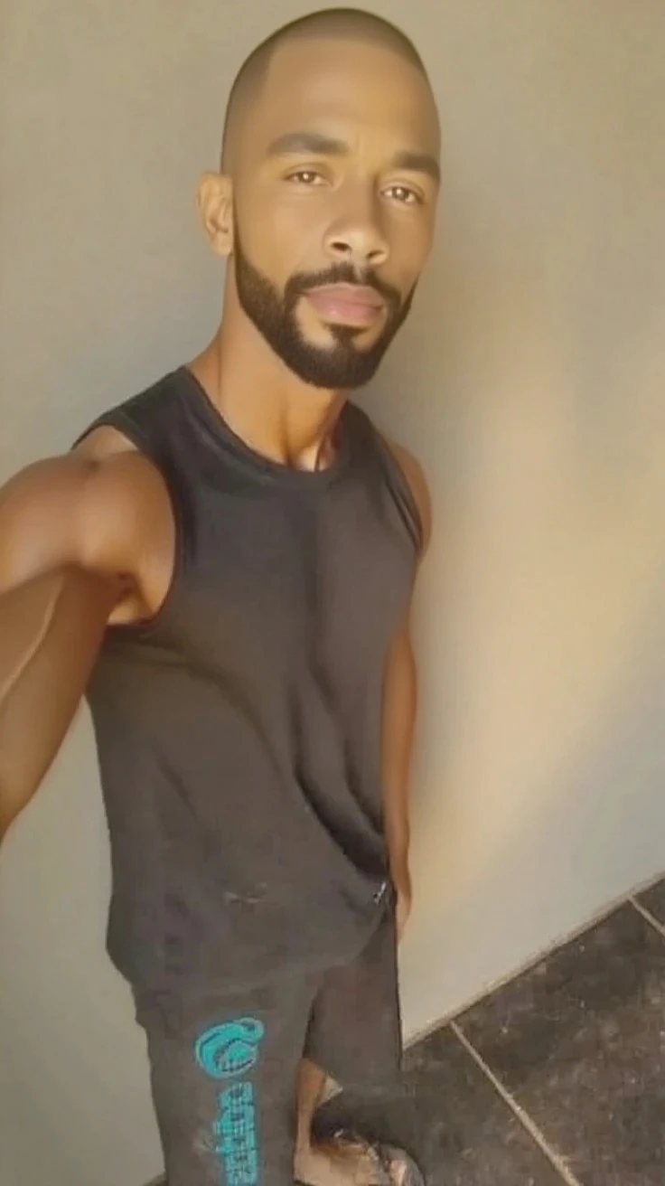 Real image of a latin model man with short black hair athletic body, short beard, shirtless, black pants, preparing snack in a kitchen with a large window. natural daylight.