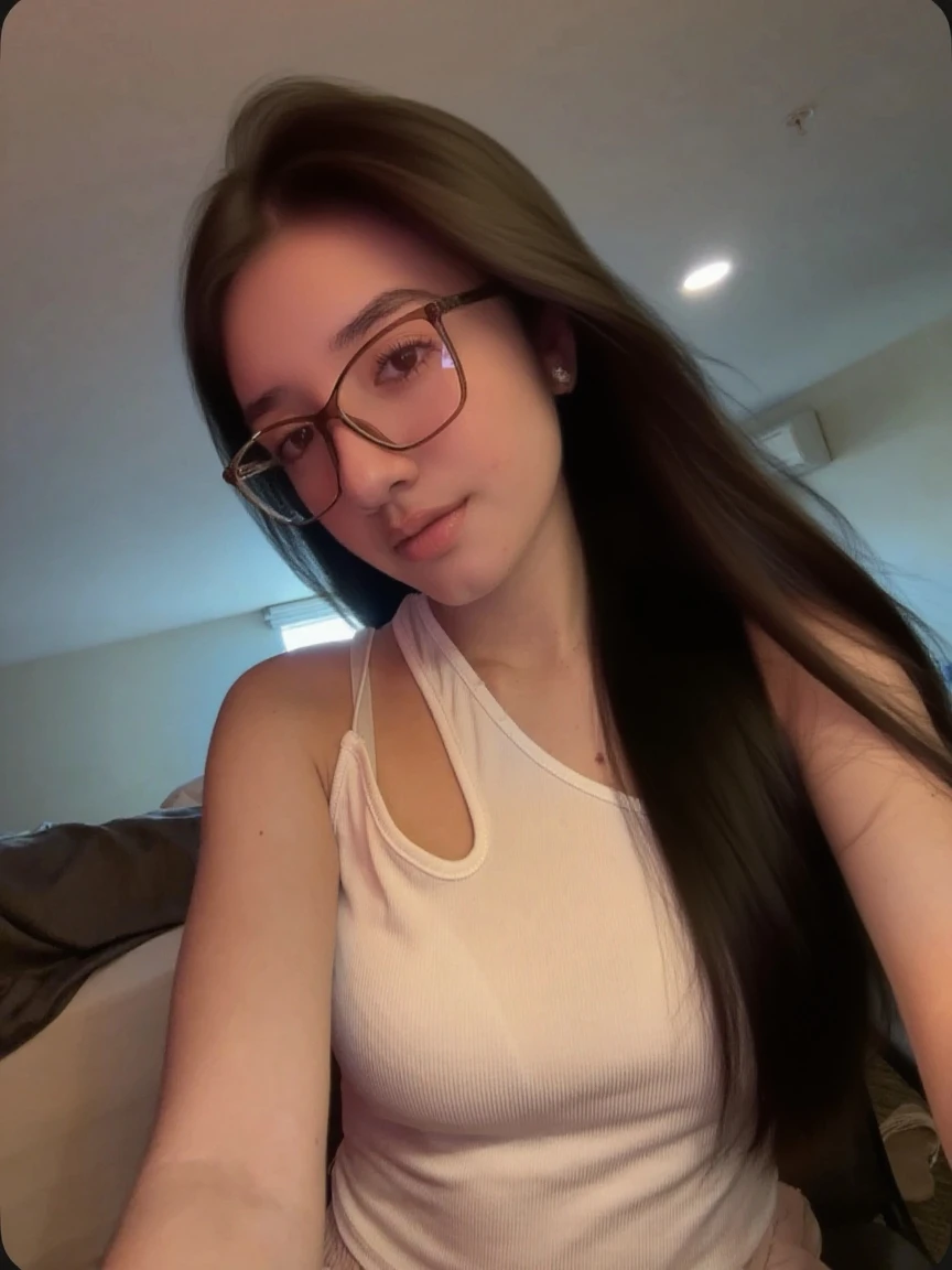 iphone photo young college woman, long tousled brunette hair, no makeup, beautiful smile, lying on her bed in her messy dorm room, wearing glasses, tank top, shorts . large depth of field, deep depth of field, highly detailed