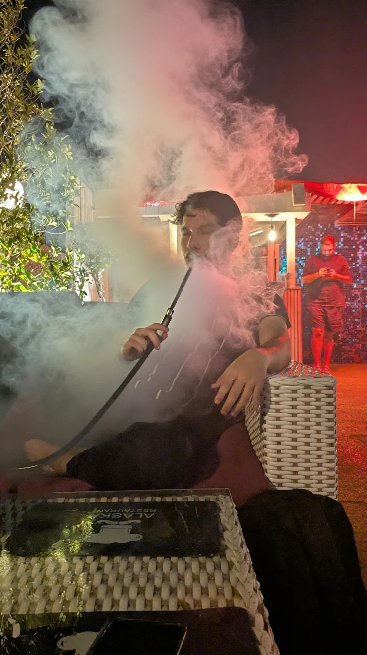 Best image quality, ultra realism, seated man, 20 year old face, rounded head, hair forehead, glasses lens matte black, no beard, round chin, smoke coming out of mouth, smoke covering mouth and nose, shiny silver chain, bodybuilder's body, skin texture, well-defined pixels, well-defined shapes, well-defined image