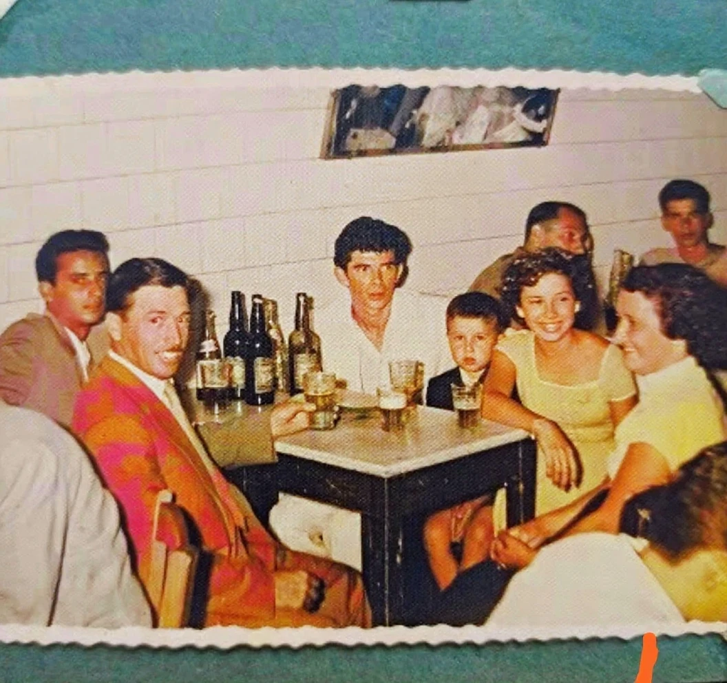 a black and white drawing, A group of people drinking alcohol around a table at a inn, The youthful muscles have turned to fat, the bronzed flesh to paunches. The men are balding or greying, and the women's dimples have turned to wrinkles. From what they say, you learn that the city has ignored them. None of them received a hero's welcome and One of the youths has been stoned. Now they have sunk into sullen reminiscences about glorious days long ago; seven and a half years after coming home, the six surviving youths and five maidens of Athens are still fighting the darkness of Knossos.{{{{{monochrome}}}}}