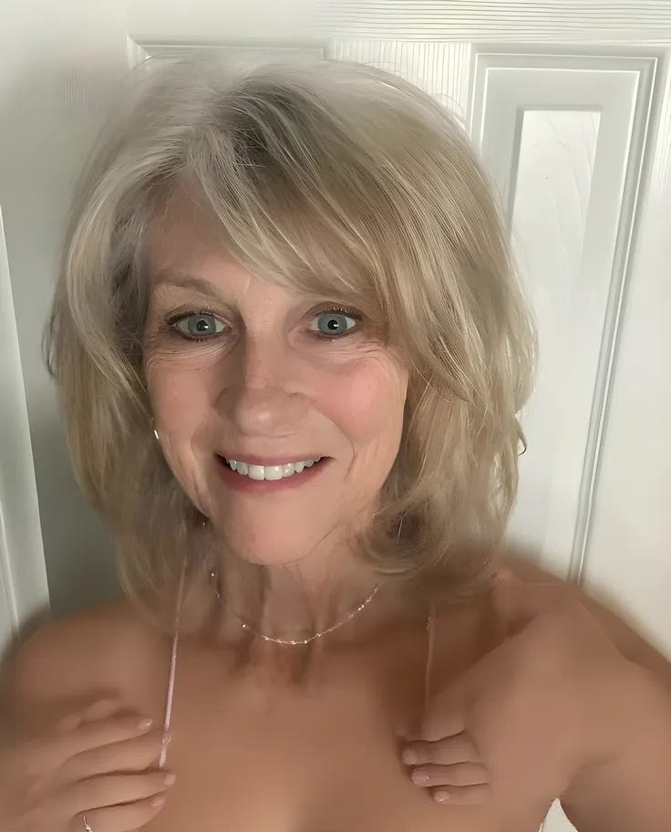 A realistic, photorealistic image of Felicidad, (a 80-year-old Finnish woman), (((white blonde and medium length hair))), smiling and seducing, ((taking a selfie inside the navy-blue bedroom)), (((round face))), (medium straight hair), (( and )),  bone