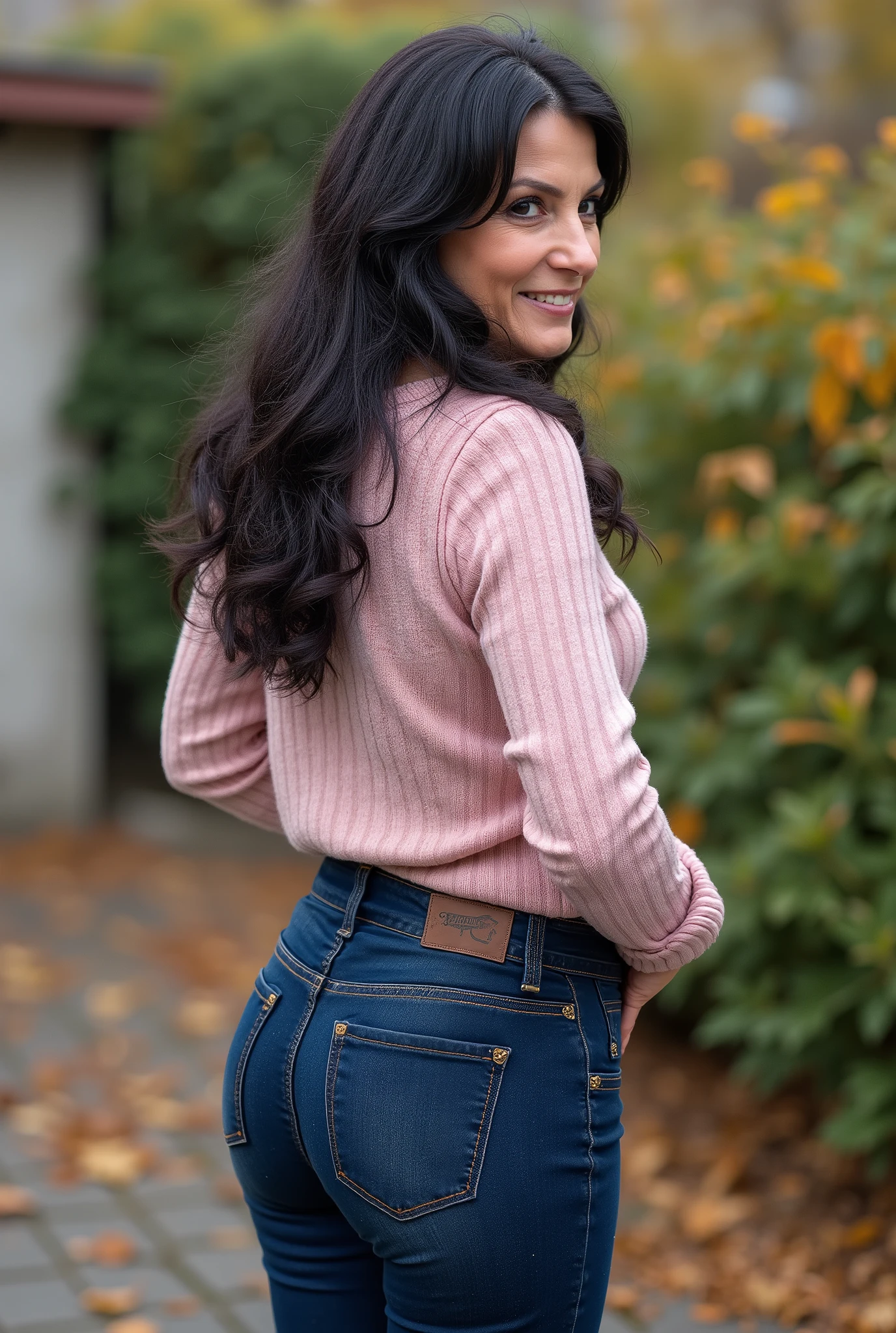 hyperrealistic full-body true rear portrait of mature European woman with unmistakable mom presence captured directly from behind with perfect vertical alignment, long dark wavy hair with natural texture variation loosely gathered and secured with dark blue plastic claw clip allowing elegant tendrils to escape framing neck area, head turned precisely at 45-degree angle over right shoulder revealing partial profile with graceful mature beauty showing refined features and subtle signs of aging adding character, wearing ultra-skinny dark blue jeans with exceptional second-skin fit containing high elastane percentage creating perfect fabric tension across wide pear-shaped buttocks with characteristic pocket placement highlighting wide hip structure contrasting dramatically with notably slim waist, pronounced hourglass body shape with significant proportional difference between hip and waist measurements creating classical feminine silhouette, pale pastel rose form-fitting knit sweater with authentic textile weave showing subtle ribbing pattern at cuffs and hemline, deliberately tucked slightly into waistband at back creating emphasis on waistline and enhancing natural curves, standing with weight slightly shifted to one leg creating subtle natural asymmetry in quiet secluded backyard area with minimal landscaping elements, soft blurred background with muted autumn foliage creating professional bokeh effect enhancing subject isolation, captured in diffused overcast autumn daylight creating even illumination with subtle directional quality, cinematic ultra-detailed 8k photography style with perfect technical execution