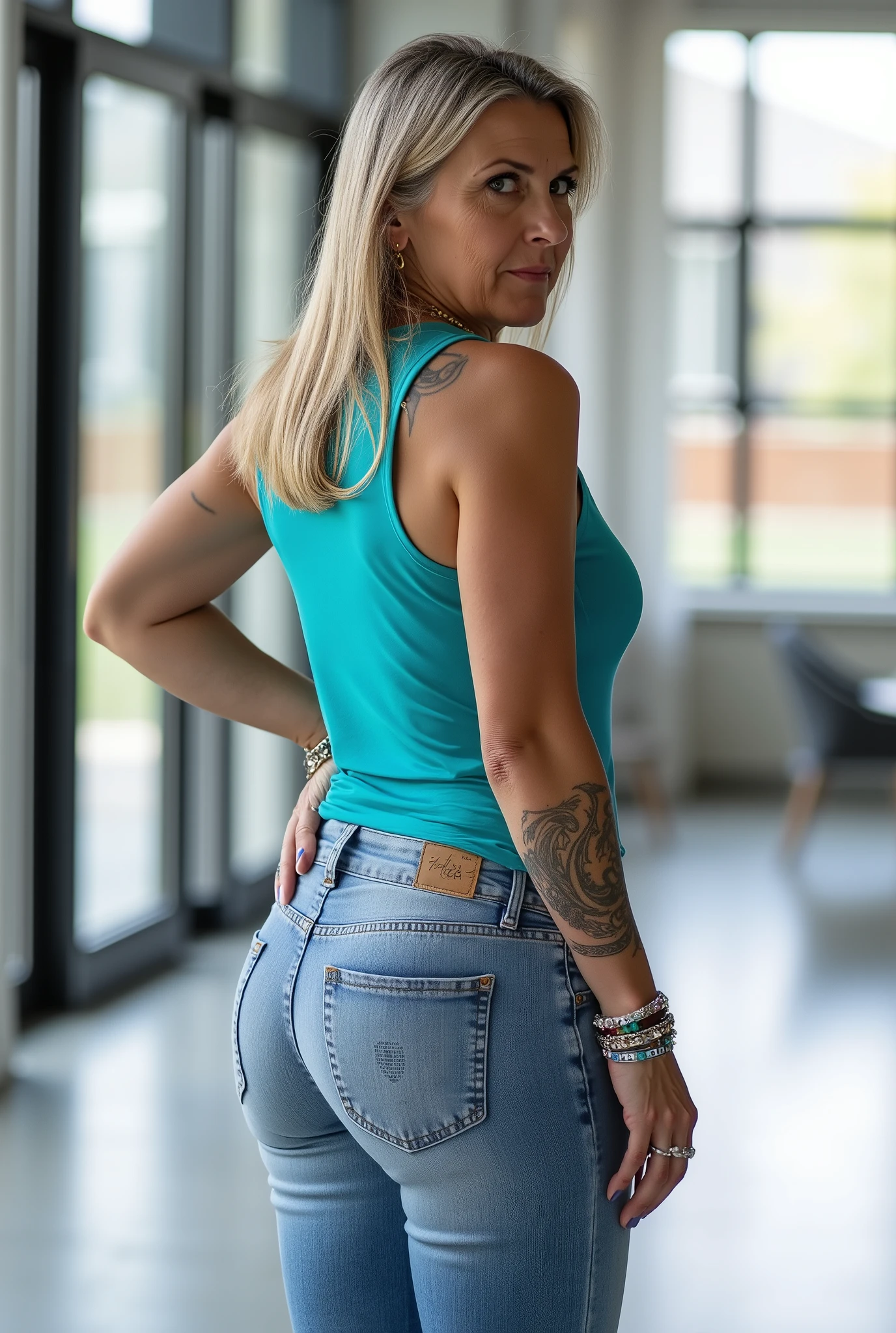 Ultra-realistic full-body rear shot portrait of a mature European woman in her late 50s, visual focus on buttocks, standing confidently in a bright modern loft with wide glass windows and soft natural daylight, facing away from the viewer. She has a naturally mature, slightly more curvy and stout body — soft, full curves around the hips, thighs, waist, and upper arms, with realistic proportions typical for her age. one hand resting lightly at her hip while the other arm falls naturally at her side, creating an elegant S-curve that emphasizes her curves. The slightly low three-quarter angle adds depth and highlights her hips and thighs, while drawing attention to the fit of her tight light-washed jeans. Her straight, pin-straight side-parted long blonde hair falls just past her shoulders with visible grey strands. She wears a turquoise sleeveless tank top tucked into her jeans, showing small tasteful tattoos on her arms. She accessorizes with multiple bracelets, layered necklaces, several rings, and long fingernails neatly manicured and painted glossy blue. Her expression is stern, serious, and commanding, with a focused, authoritative gaze. The scene has cinematic clarity, realistic depth of field, soft natural lighting, and professional daylight color grading, highlighting natural textures, her curvy silhouette, and creating a more intriguing, dynamic composition.