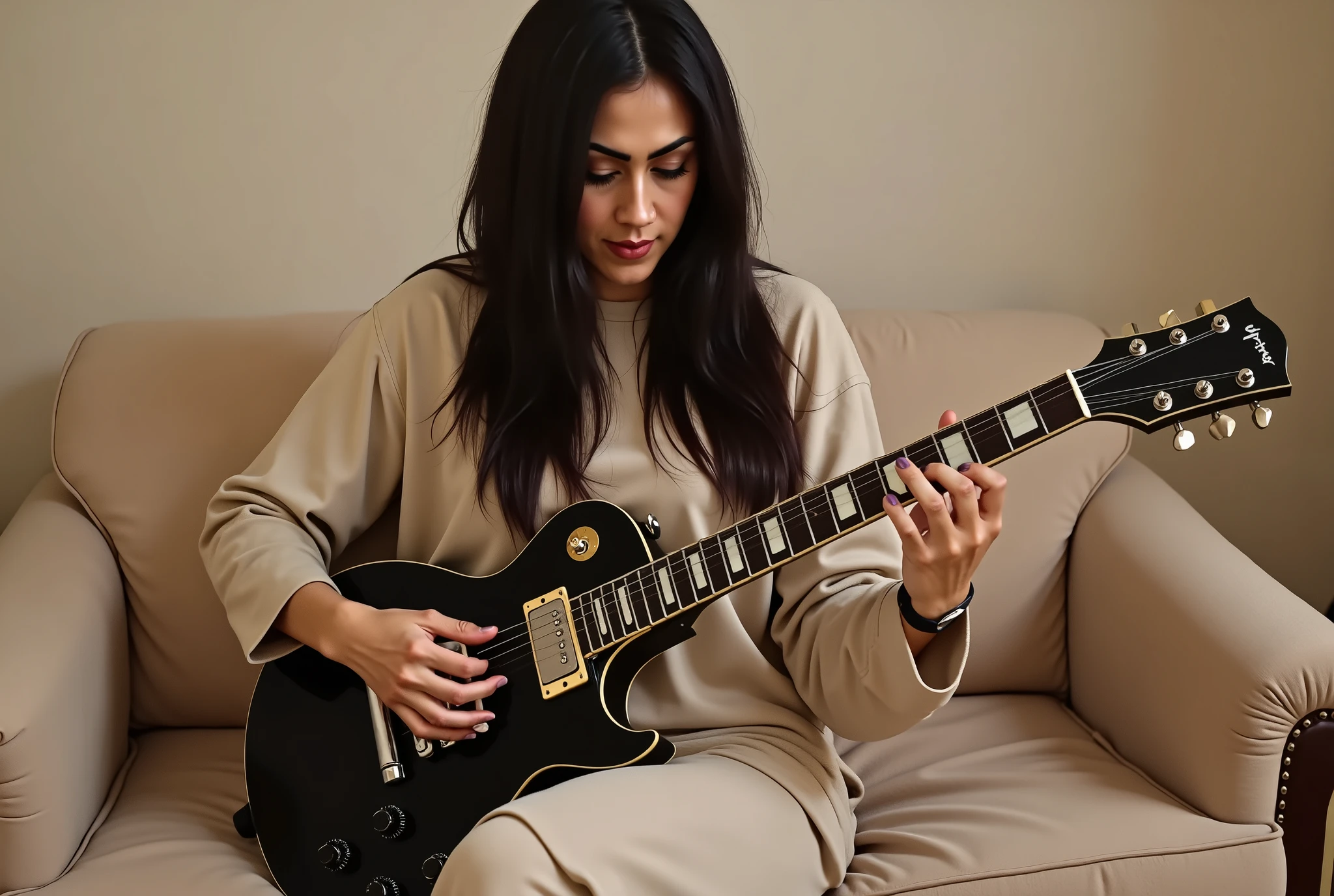 This picture features a woman with long, dark hair sitting on a **light beige or tan couch**, playing a **dark electric guitar**.
