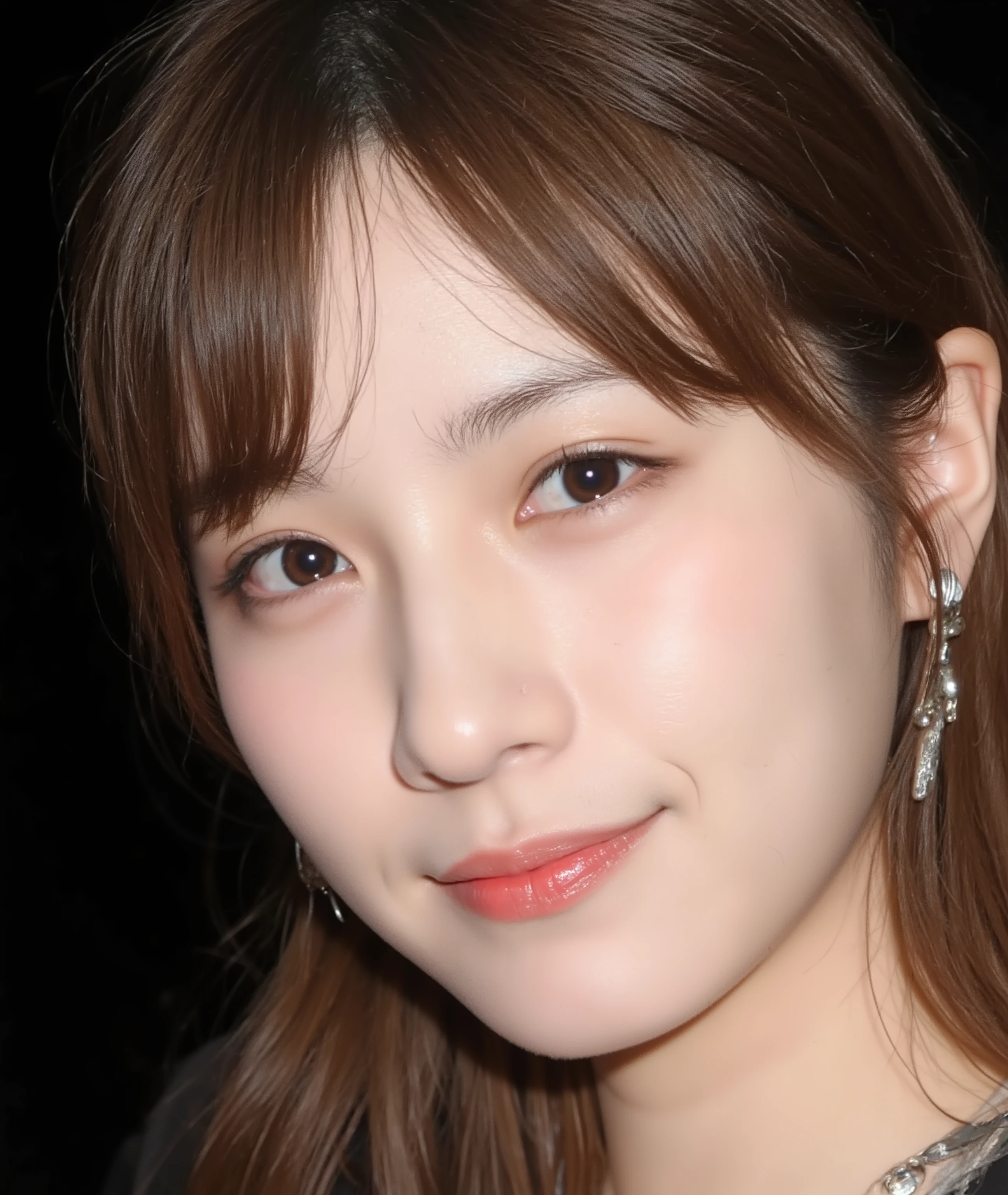 The image is a close-up photograph of a young Asian woman with a fair complexion. Her face dominates the frame, occupying the majority of the image, with her eyes, nose, and lips prominently visible. She has large, almond-shaped eyes with long, thick eyelashes, and her skin is smooth and soft. Her lips are full and slightly parted, revealing a natural, rosy hue. She wears a small silver stud earring in her left ear, adding a subtle touch of personal style.
Her hair is long, dark brown with subtle highlights, and it partially covers her forehead, giving a slightly tousled, casual look. The background is out of focus, but it appears to be a dark, possibly indoor setting, which emphasizes her face and provides a stark contrast to her light complexion. She is wearing a black garment, possibly a top or a sleeve, which is visible at the bottom of the image. The overall mood of the photograph is intimate and personal, capturing a candid moment with a natural, unfiltered aesthetic.