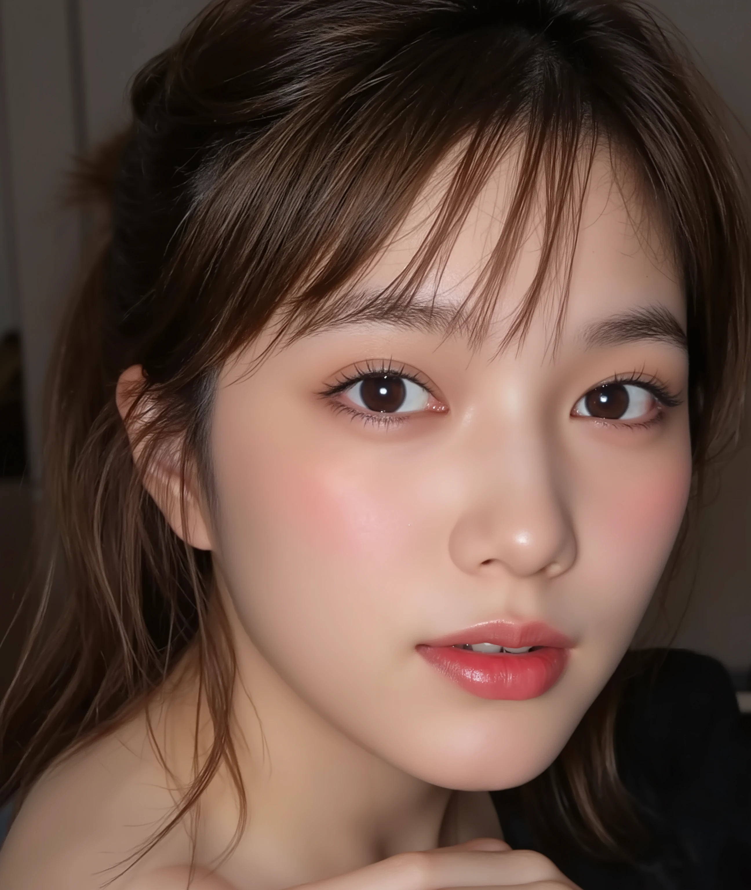 The image is a close-up photograph of a young Asian woman with a fair complexion. Her face dominates the frame, occupying the majority of the image, with her eyes, nose, and lips prominently visible. She has large, almond-shaped eyes with long, thick eyelashes, and her skin is smooth and soft. Her lips are full and slightly parted, revealing a natural, rosy hue. She wears a small silver stud earring in her left ear, adding a subtle touch of personal style.

Her hair is long, dark brown with subtle highlights, and it partially covers her forehead, giving a slightly tousled, casual look. The background is out of focus, but it appears to be a dark, possibly indoor setting, which emphasizes her face and provides a stark contrast to her light complexion. She is wearing a black garment, possibly a top or a sleeve, which is visible at the bottom of the image. The overall mood of the photograph is intimate and personal, capturing a candid moment with a natural, unfiltered aesthetic.