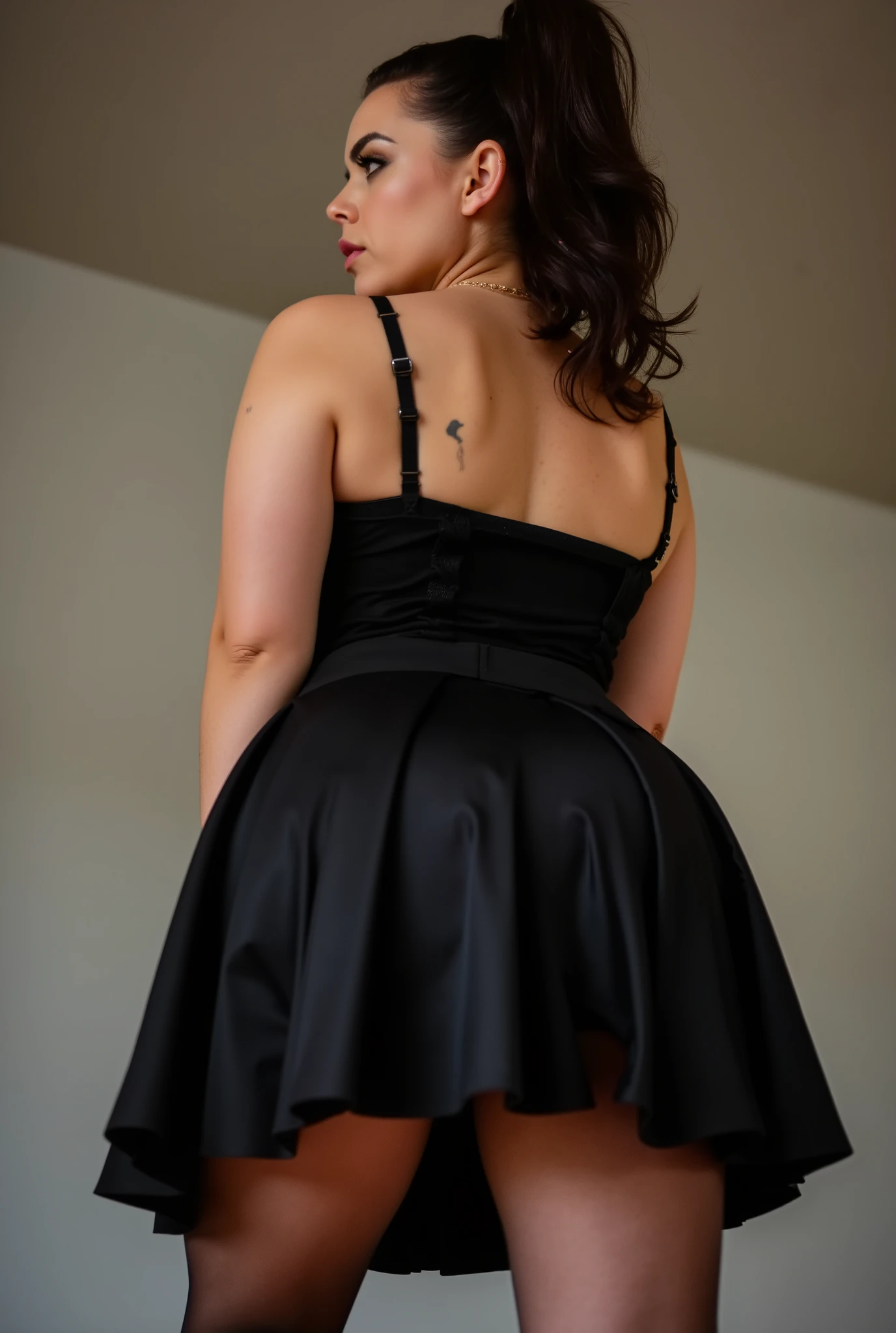 imposing rear-angle portrait of domineering European woman with stout powerful build, wide hips and thick strong legs in authoritative stance, minimal head turn revealing just a glimpse of stern profile with intense sidelong glare, wavy dark brown hair inspired by rockabilly style and tied into long full ponytail, fitted black pleated skirt with sheer black stockings showcasing her substantial curves, black tank top with thin straps along her broad back, small tattoos on arms, back deliberately arched to assert dominance while emphasizing her full rounded buttocks, shot from extremely low submissive angle with ceiling visible beyond her towering form, bright daylight creating dramatic shadows that accentuate her commanding presence