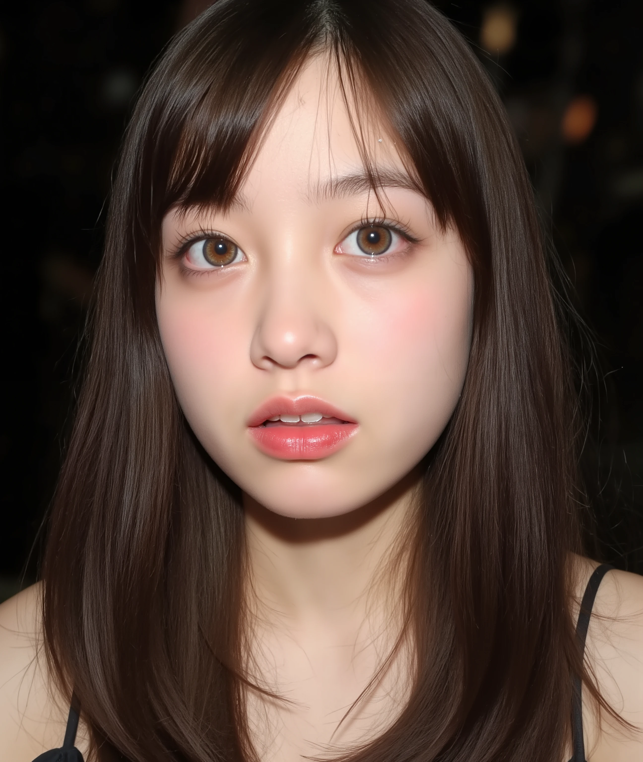 The image is a close-up photograph of a young Asian woman with a fair complexion. Her face dominates the frame, occupying the majority of the image, with her eyes, nose, and lips prominently visible. She has large, almond-shaped eyes with long, thick eyelashes, and her skin is smooth and soft. Her lips are full and slightly parted, revealing a natural, rosy hue. She wears a small silver stud earring in her left ear, adding a subtle touch of personal style.
Her hair is long, dark brown with subtle highlights, and it partially covers her forehead, giving a slightly tousled, casual look. The background is out of focus, but it appears to be a dark, possibly indoor setting, which emphasizes her face and provides a stark contrast to her light complexion. She is wearing a black garment, possibly a top or a sleeve, which is visible at the bottom of the image. The overall mood of the photograph is intimate and personal, capturing a candid moment with a natural, unfiltered aesthetic.