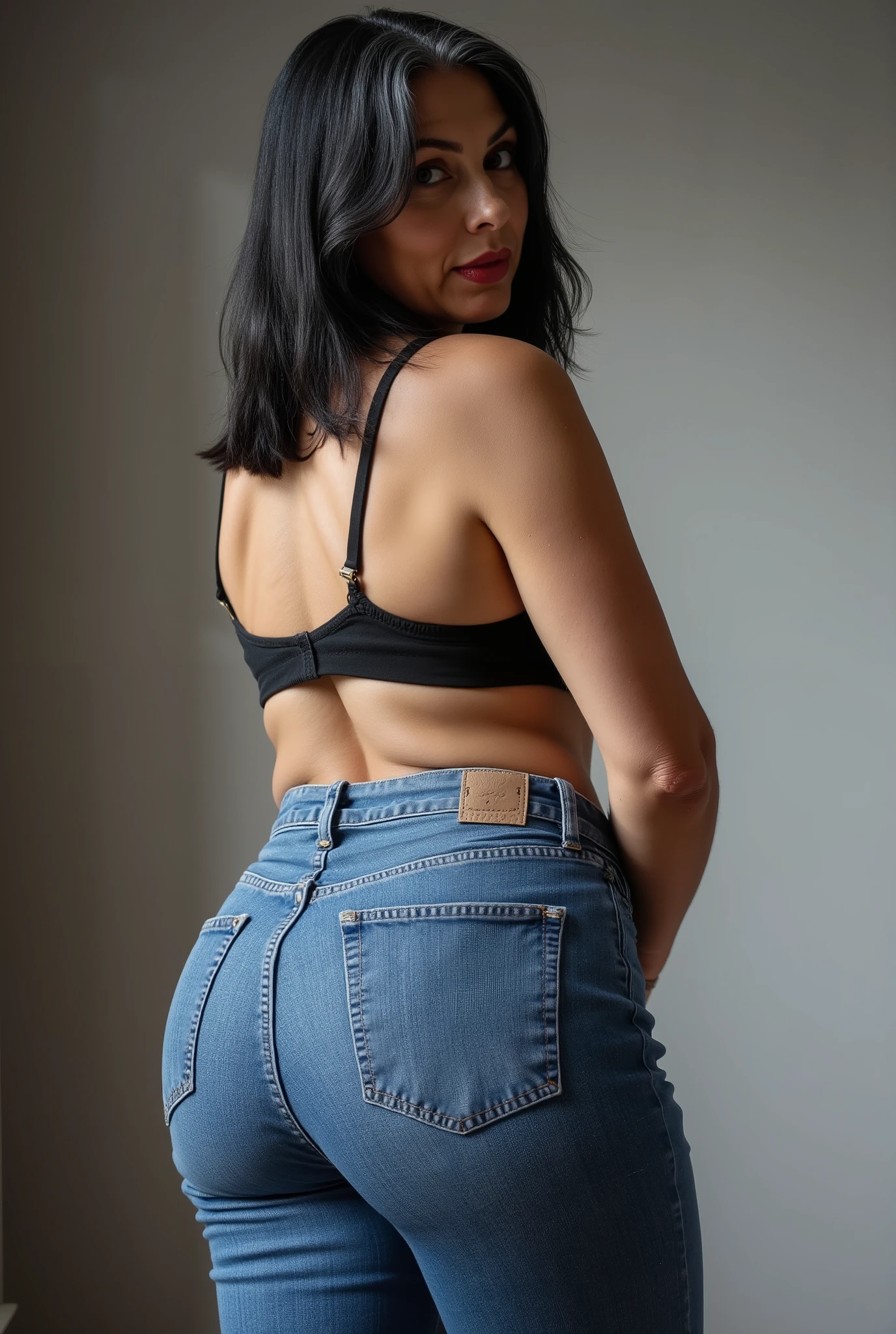 Lowangle,A european, mature woman, 60 years old, stands in jeans, her back to the camera, positioned on the floor directly behind her for a steep straight rear view. The composition is close, visually focusing on the curves of her hips and buttocks, while she glances down over her shoulder to make eye contact with the lens. Condescending expression, crow's feet, glossy red lipstick, looking down on viewer, mom vibes, realistic mature body proportions. Straight shoulder length hair dyed black with grey roots, wearing lace bra. Soft indoor lighting highlights the denim texture and her smooth silhouette, with a blurred minimalist background for emphasis. Cinematic, intimate, stylish feel.