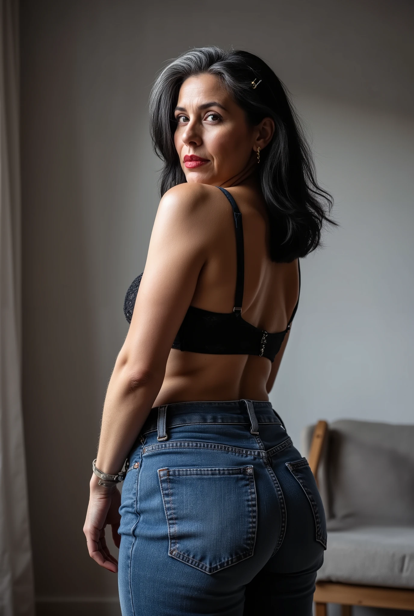 Lowangle,A white european mature woman, 60 years old, stands in jeans, her back to the camera, positioned on the floor directly behind her for a steep straight rear view. The composition is close, visually focusing on the curves of her hips and buttocks, while she glances down over her shoulder to make eye contact with the lens. Condescending expression, crow's feet, glossy red lipstick, looking down on viewer, mom vibes, realistic mature body proportions, aged slightly wrinkled skin. Shoulder length hair dyed black with grey roots, cute hairpins. wearing lace bra. Soft indoor lighting highlights the denim texture and her smooth silhouette, with a blurred minimalist background for emphasis. Cinematic, intimate, stylish feel.