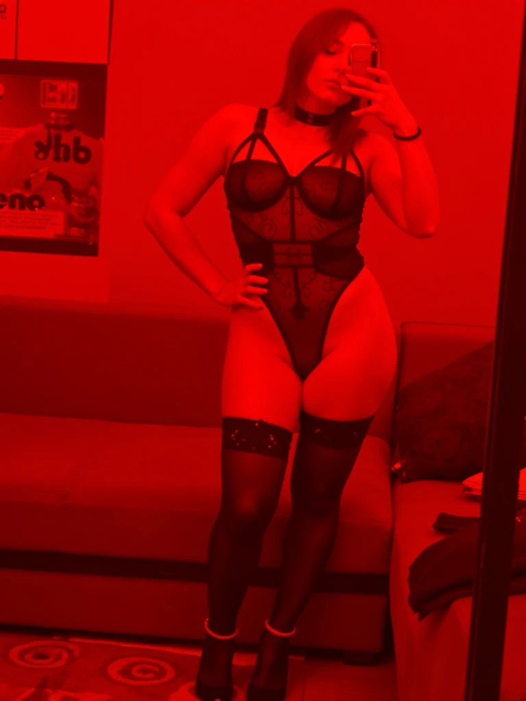 there is a woman in a black lingerie sitting on a bed, picture taken ???????????, molestar, view from back, Sensual, sensual y atractivo, Vista posterior, full lenght shot, photo from the back, illuminated ???????????, curvy accentuated booty, polvo espeso y tonos rojos, seen from the back, shot from the back, red neon