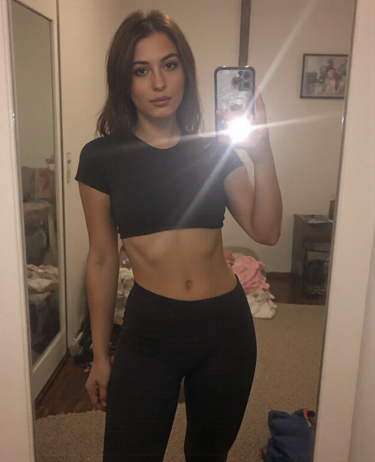 24-year-old Caucasian Spanish woman taking a selfie in front of the mirror with a side angle, raising her butt and with her cell phone in her hand, The phone is an iPhone 14 with a gray case, She is dressed in a multi-colored tank top and tight black tail-lifting shorts., The photos must be as real as possible without any type of deformation and taking care of every detail on the woman's body., hyperrealistic images with the highest possible resolution, She has a beautiful body with big breasts and a big round ass