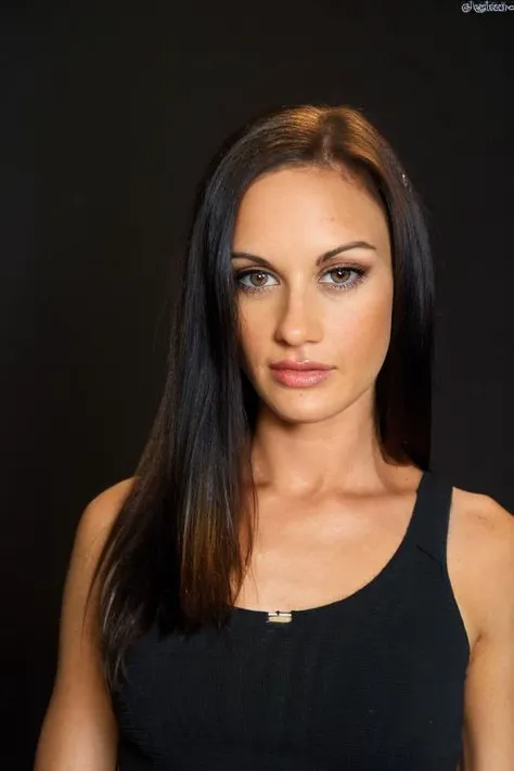 a portrait of  <lora:Taylor_Rain_pornstar:1> in front of a [plain black background] wearing a black tank top, collarbone, [headshot], [centre frame], looking at the camera, facing the camera,
 dynamic lighting, long straight hair,
photorealistic, high detail, detailed, masterpiece, 8k, highres, flawless, colour, professional