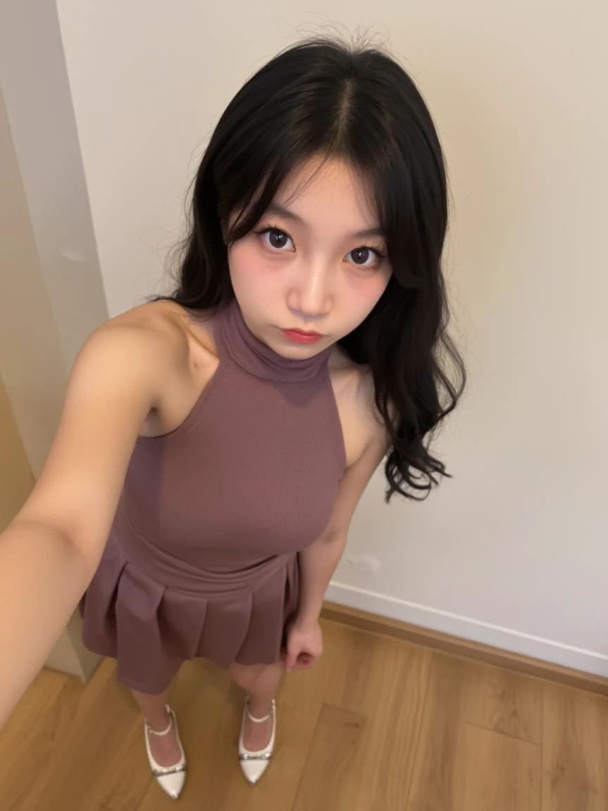 The image is a photograph featuring a young Asian woman with fair skin and long, wavy black hair. She has a petite physique with a slender build and small breasts. She is wearing a sleeveless, mauve-colored top with a high neckline and a pleated skirt, both made of a soft, knit fabric. Her outfit is modest, with no visible undergarments. She has a pair of white, high-heeled shoes with a metallic finish, which adds a touch of elegance to her attire.

The woman's facial expression is slightly pouty, with her lips pursed and her eyes looking directly at the camera. She has a delicate, youthful appearance with minimal makeup, and her gaze is direct and intense. She stands in an indoor setting with a light-colored wall and a wooden floor. The lighting is soft, coming from an unseen source, creating a warm and inviting atmosphere. The overall composition of the photograph is slightly tilted, giving it a dynamic and intimate feel, as if the viewer is looking down on the subject. The photograph captures a moment of casual elegance and confidence.