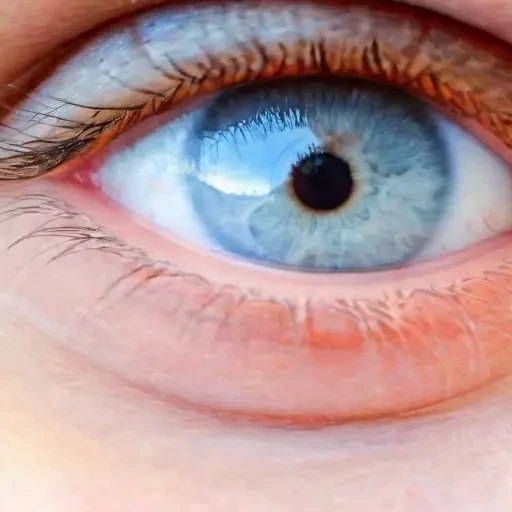 grey blue eye of a child, reflection of clouds, extreme close up of an eye