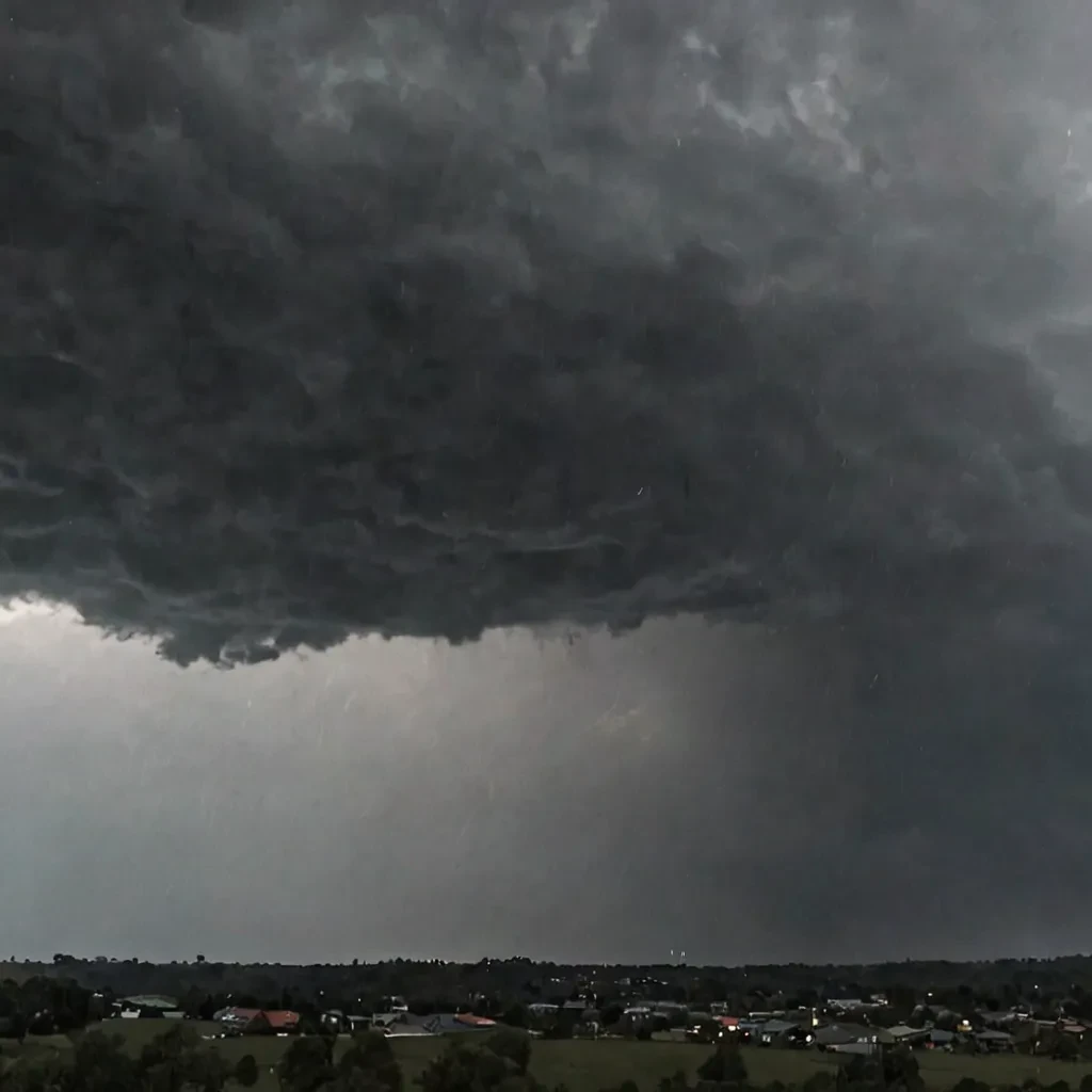 Intense, dark clouds with heavy rain pouring down, possibly with streaks of rain visible against the sky.