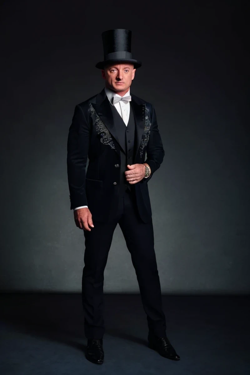 mark kelly <lora:senate_006_mark_kelly:0.65> , face closeup, face focus, shirt, formal, suit, collared shirt, white shirt, jacket,
Dressed in a magician's outfit with a top hat, standing in front of a stage,  rabbit out of a hat,
best quality, masterpiece, HDR, professional, studio quality, highres,