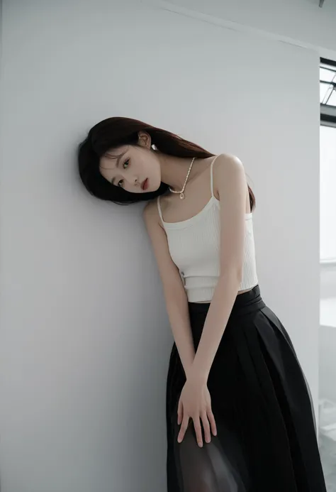 A asian woman wearing a black skirt is standing by a white wall, with her left hand placed on her waist and her right hand on her neck.