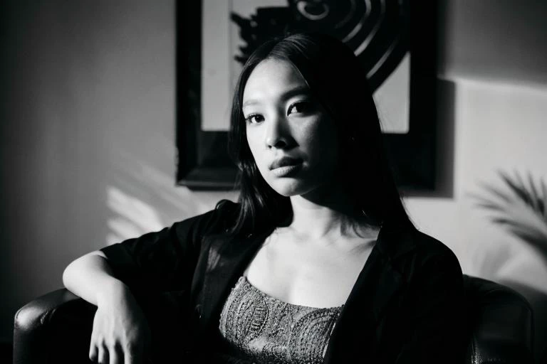 jesshong, 1girl, looking at viewer, portrait, sitting on arm chair, shadows, black and white, smoke, style karsh, style<lora:jesshong_v2-000004:1>
