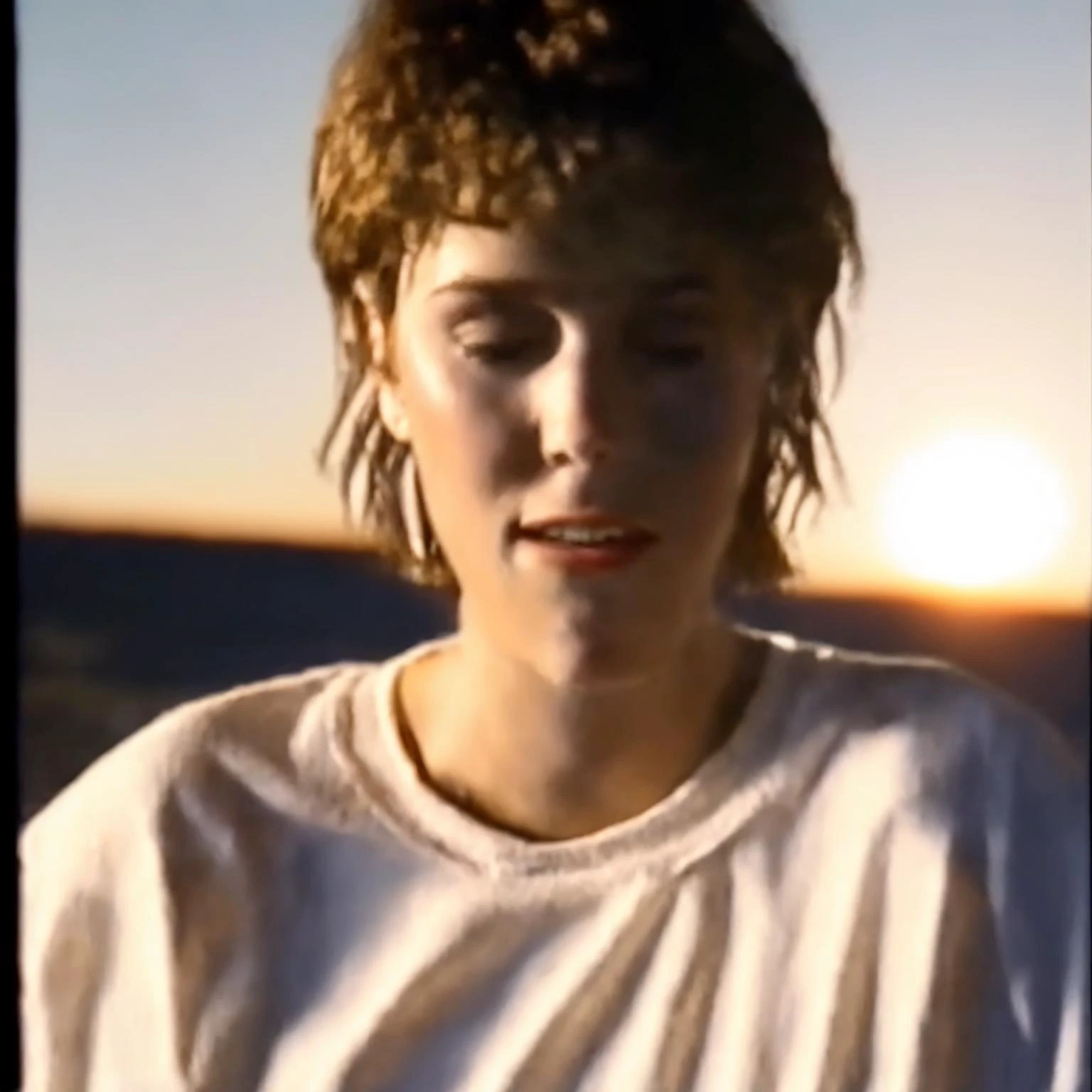 90VHS, vhs still from tv, vhs from documentary, vhs commercial, (( a woman with a few freckles, round eyes and short messy hair shot outside, wearing a white t shirt, staring at camera, chapped lips, on VHS style image like 80s)), ((high quality:1.2, masterpiece:1.2)),absurdres, high resolution,(8k resolution), 8k, 8kres, 8k res,high details, detailed and intricate, intricate details, high intricate details, absurd amount of details,((upper body:1.2)), portrait, Realism, VFX,TXAA,RTX,Shaders, Natural Lighting,Volumetric Lighting, Volumetric Light, Volumetric, <lora:90VHS-03:1>
