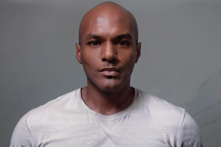 <lora:rhyheimsv3:1> rhyheims, black man, bald, dark skin, brown eyes, professional studio quality modeling headshot, 4K, simple dark background, dramatic lighting, neutral expression, realistic skin, fine detail, shirt, ultra realistic photograph, professional photograph, by Gucci photographer.