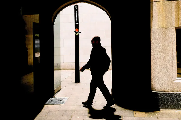 shaded street photo of a man wearing in silhouette, walking in a passageway in london, closeup, midday, film photo, flashlight, kodak portra 400