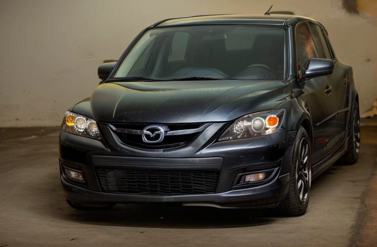 analog gloomy photo of a ((black car mazdaspeed3, <lora:3Mazdaspeed3:0.9>)), ((three quarter view)), (city streets (at night)), abandoned buildings, graffiti, ((nighttime)), horror, midnight, High Detail, Sharp focus, (photorealism), realistic, best quality, 8k, award winning, dramatic lighting, epic, cinematic, masterpiece, rim light, (ambient fog:1.3), volumetric lights:0.5, dutch angle, depth of field