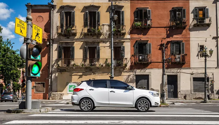 best quality, ultra-detailed, illustration, main focus (white evo car:1.1), scenery, road sign, outdoors, sign, traffic light, road, building, crosswalk, ground vehicle, street, motor vehicle, city, lamppost, tree, power lines, car, real world location, sky, utility pole, cityscape, cloud, day, sidewalk, realistic, photo background, photo (medium), milazzo with the sanctuary in the far behind <lora:evo_milazzo_SDXL-LoRA-v085:1>