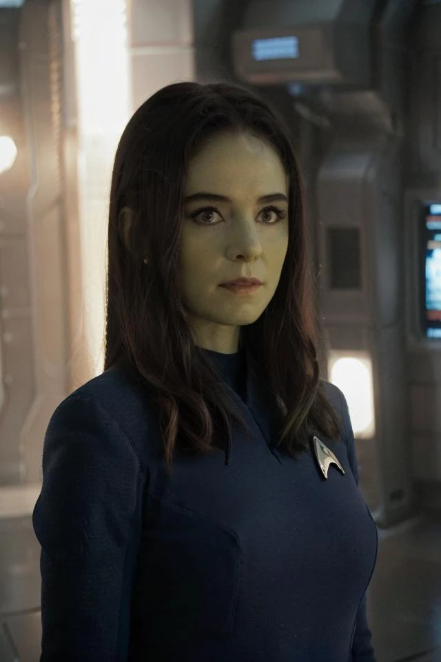 headshot of orion woman, (green skin:1.2), blue stsnwunf uniform, sci-fi starship background,